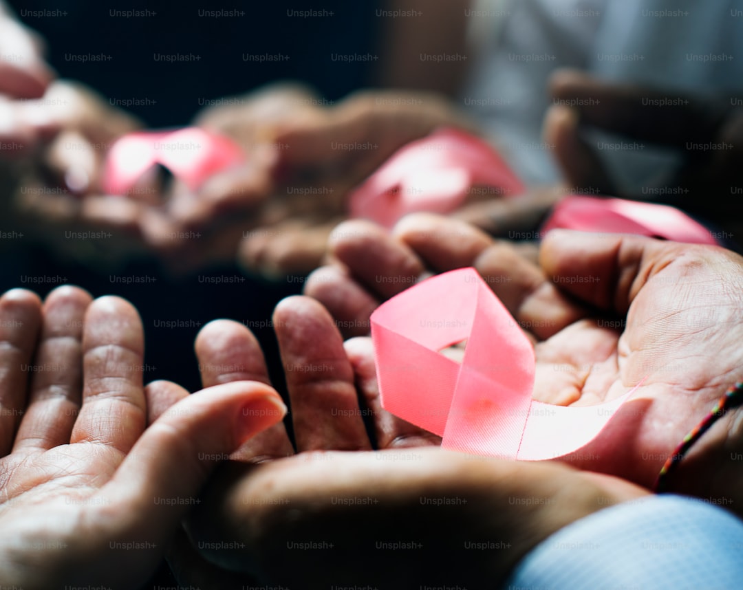 Closeup of pink ribbons on people palms for breast cancer awareness campaign