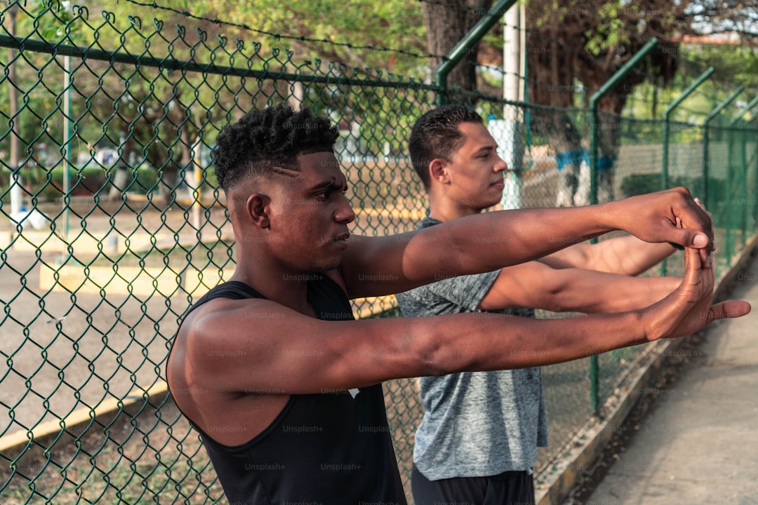 Determined male athletes doing stretching exercises on park