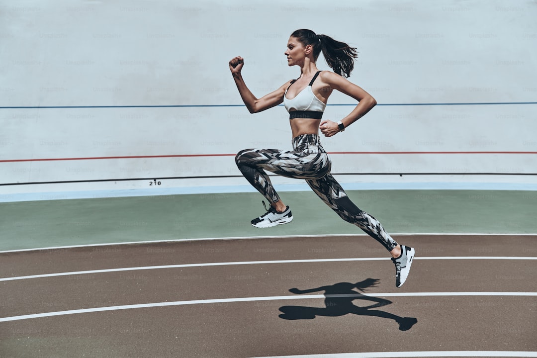 Full length of young woman in sports clothing running while exercising outdoors