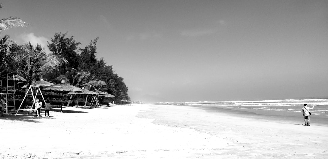 grayscale photography of man standing on seashore