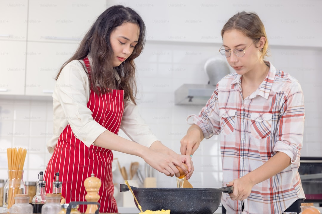 Happy woman preparing food in the kitchen. Woman cracking an egg into a frying pan