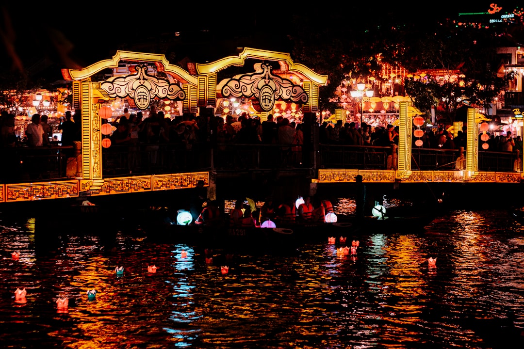 People celebrate on a bridge lit with lanterns at night.