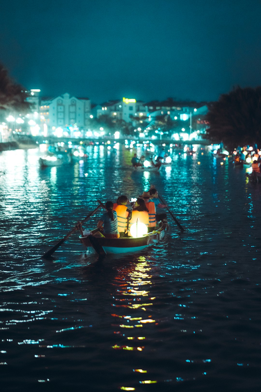 People ride a boat on a river at night.