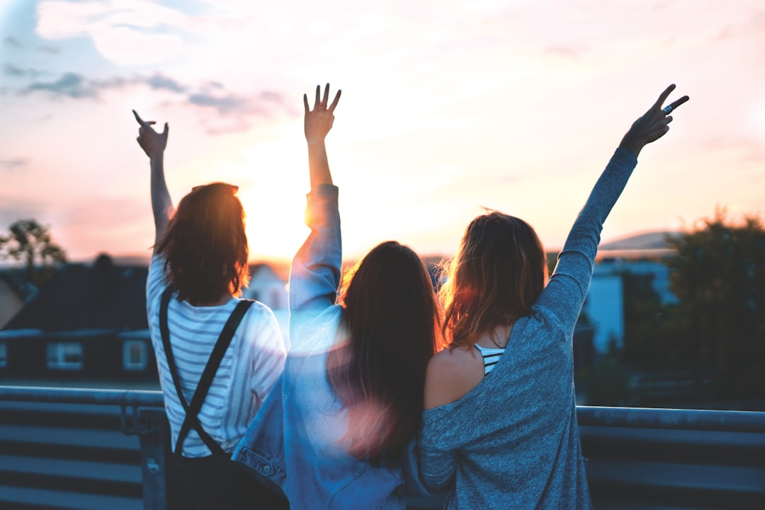 photo of three women lifting there hands