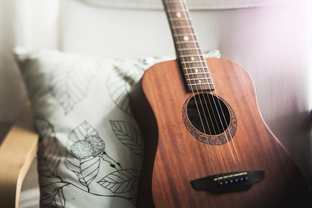 selective focus photo of brown guitar on white pillow