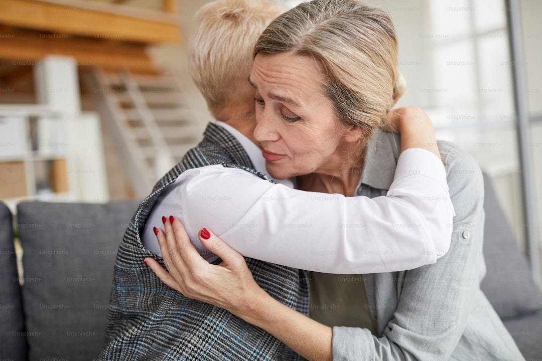 Side view portrait of caring female psychologist embracing mature woman while comforting her during therapy session, copy space