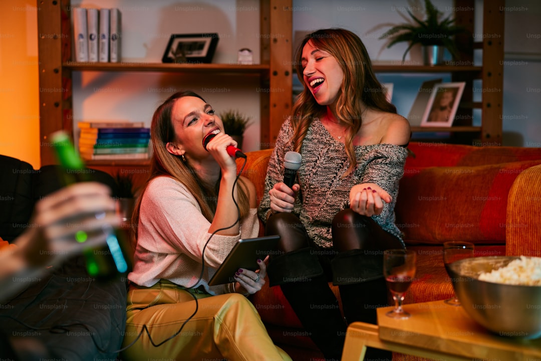 Talented girls with beautiful voices sit at home and sing a duet at karaoke night.