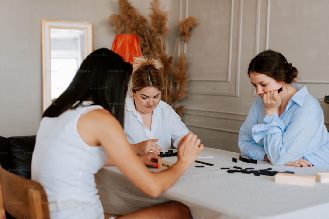 Three women sitting at a table playing a game of chess