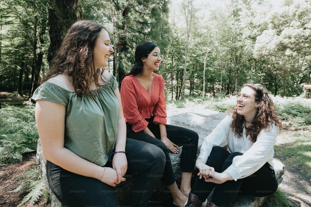 three women sitting on a rock in the woods