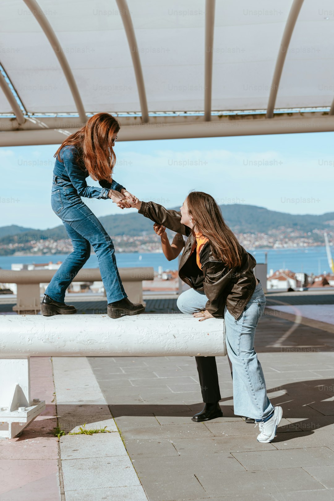 Two girls are sitting on a bench and one of them is touching the other