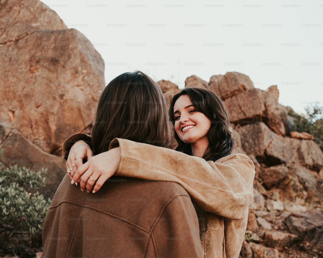 Two women hugging each other in front of a mountain