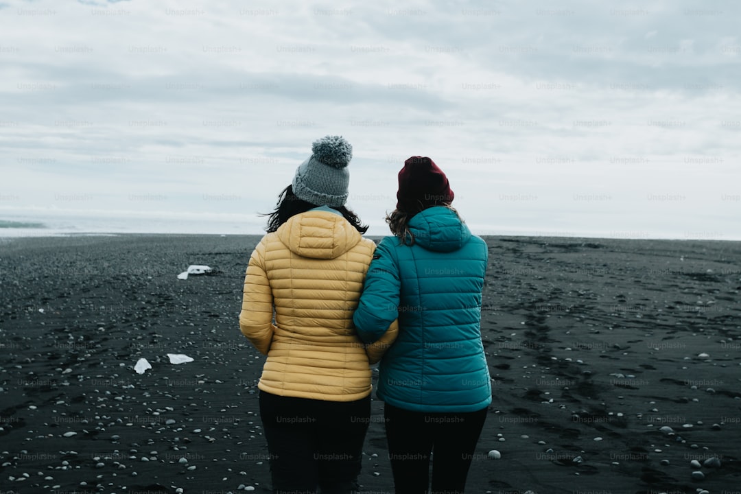 two women standing on a beach looking at the ocean