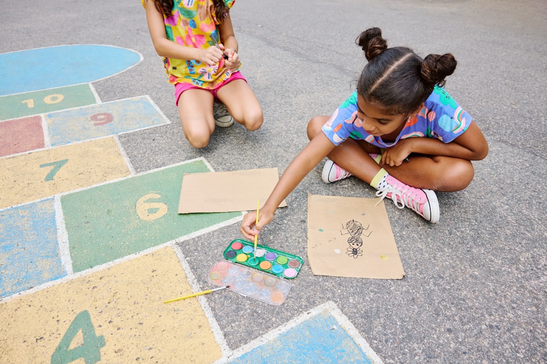 two young girls sitting on the ground playing with numbers