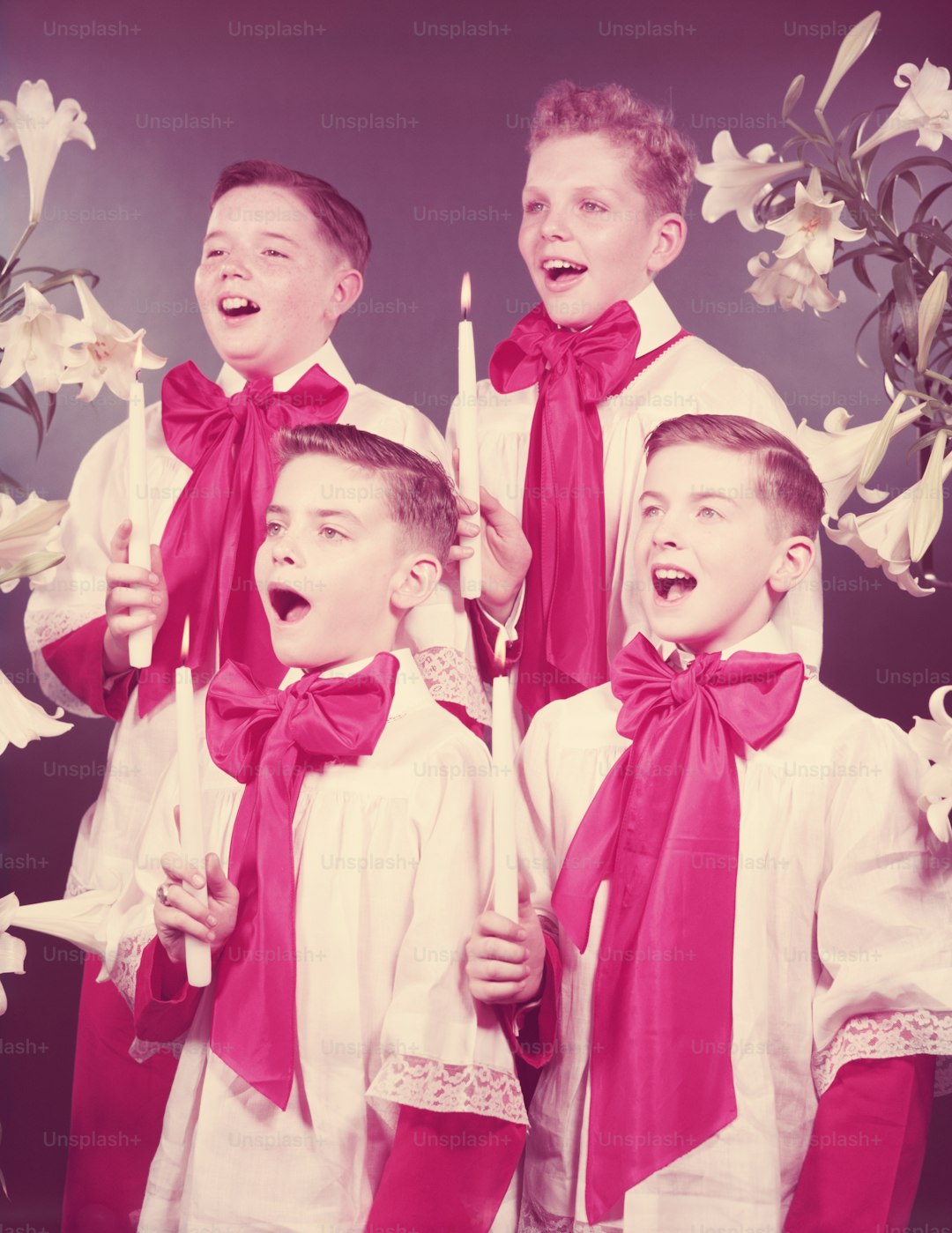 UNITED STATES - CIRCA 1950s: Four boys in choir robes, singing, holding candles.