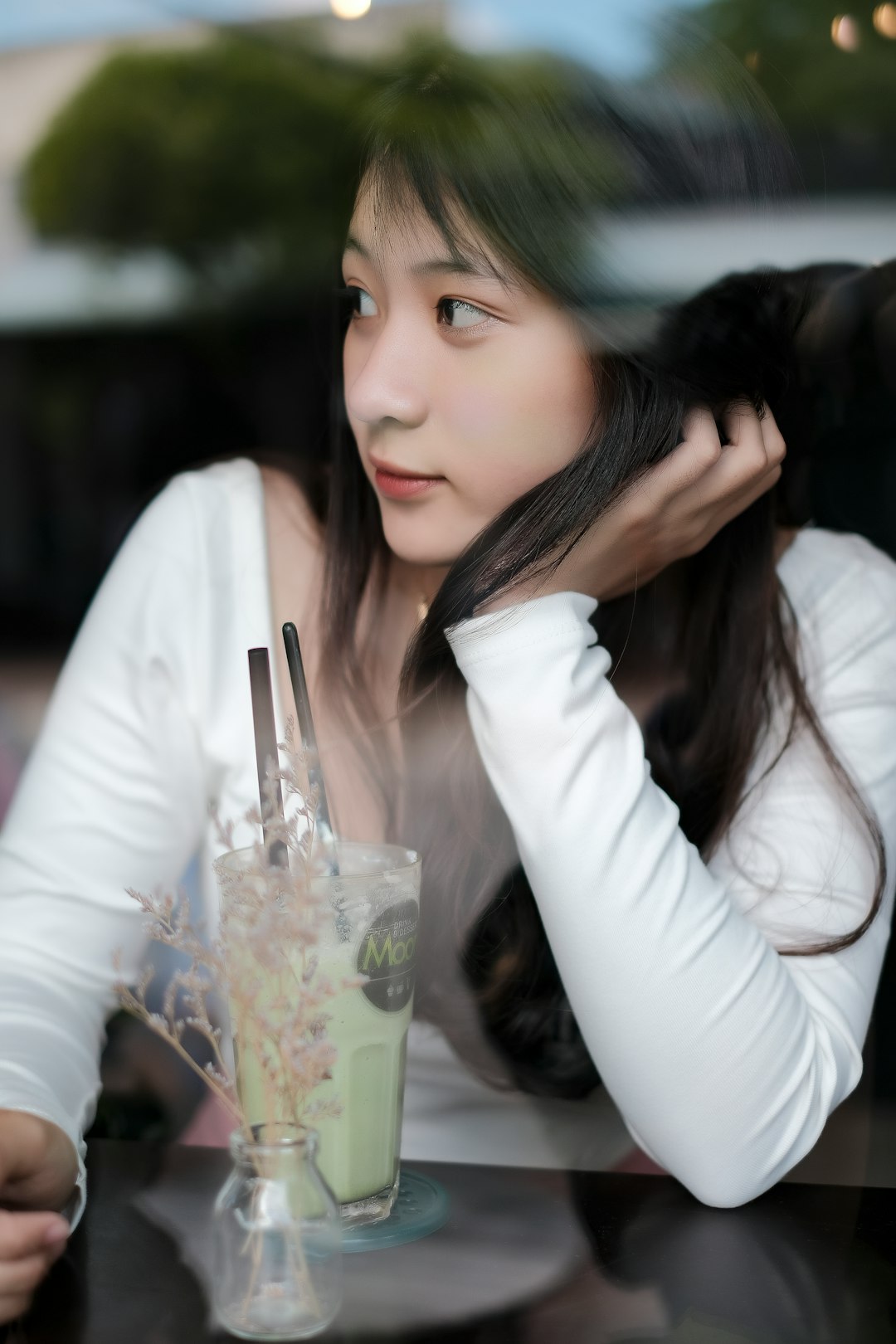 woman in white long sleeve shirt holding clear drinking glass